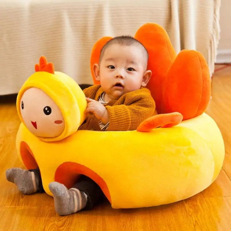 A baby dressed in a brown sweater and grey socks sits in the Cute Baby Sofa by Gigi & Jade Kids Co. The ergonomic design of this creative plush chair, featuring an orange comb and wings, resembles a cheerful cartoon chicken. The baby looks directly at the camera with a curious expression.