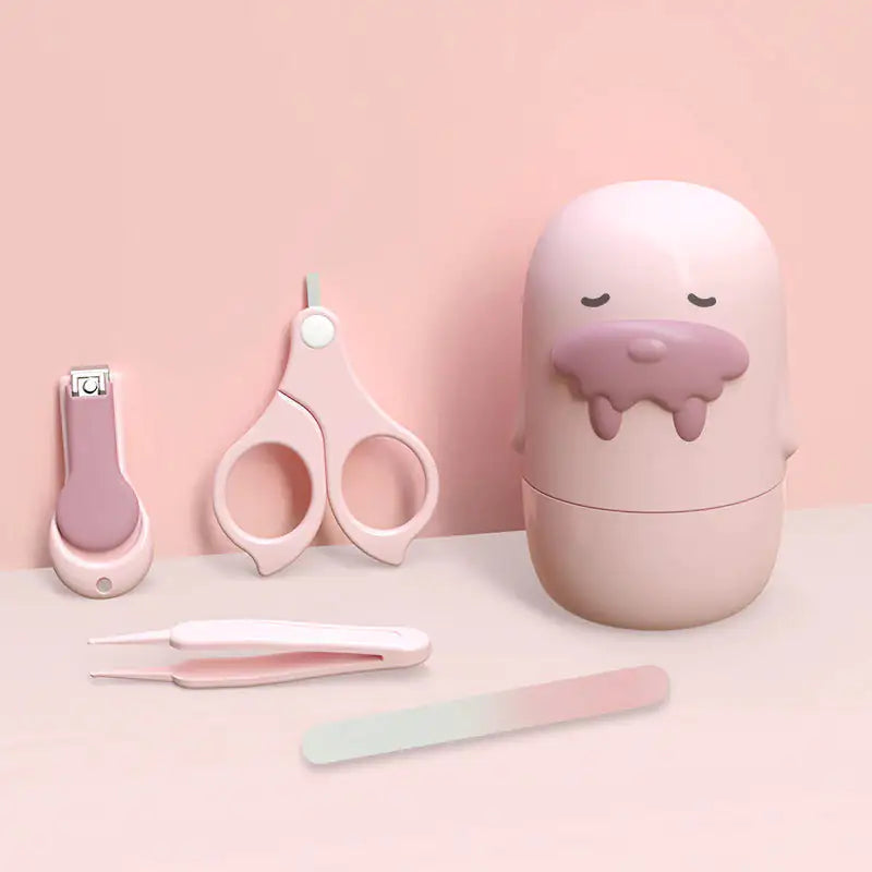 The Gigi & Jade Kids Co. Baby Nail Care Set, a collection of pastel-colored grooming tools featuring nail clippers, safety scissors, tweezers, and a nail file meticulously designed for tender nail care, is arranged next to an adorable egg-shaped storage container with a sleepy face and a drooping tongue, all set against a soft pink background.